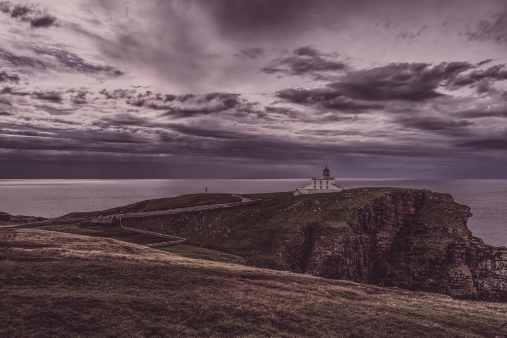 a lighthouse sitting on top of a cliff near the ocean