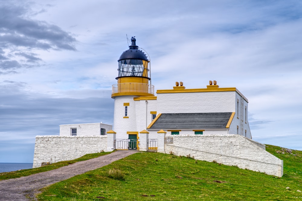 a white and yellow lighthouse sitting on top of a hill