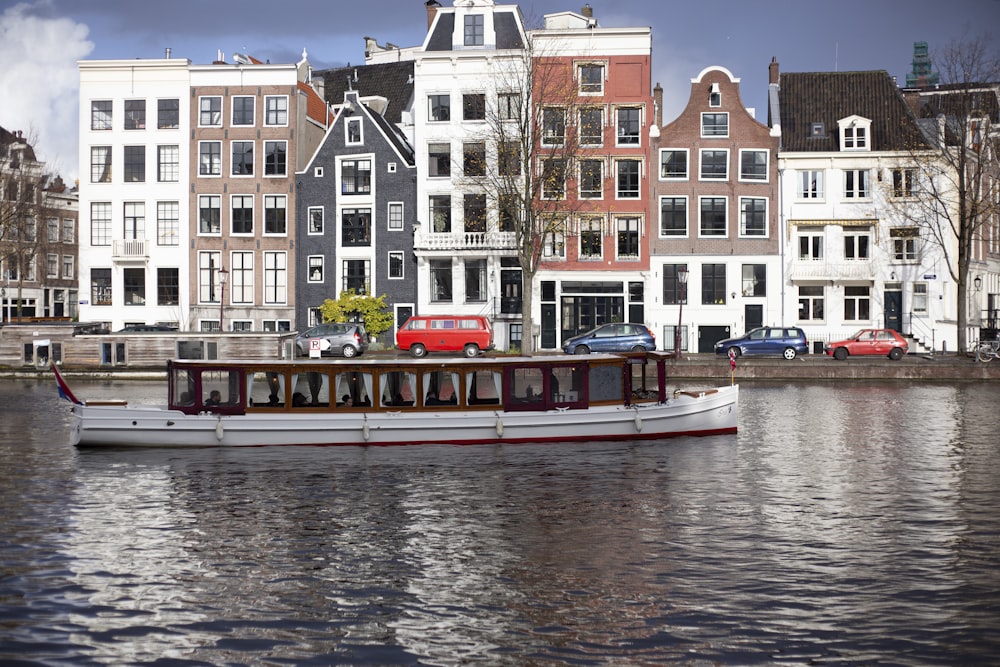 a boat on the water in front of a row of buildings