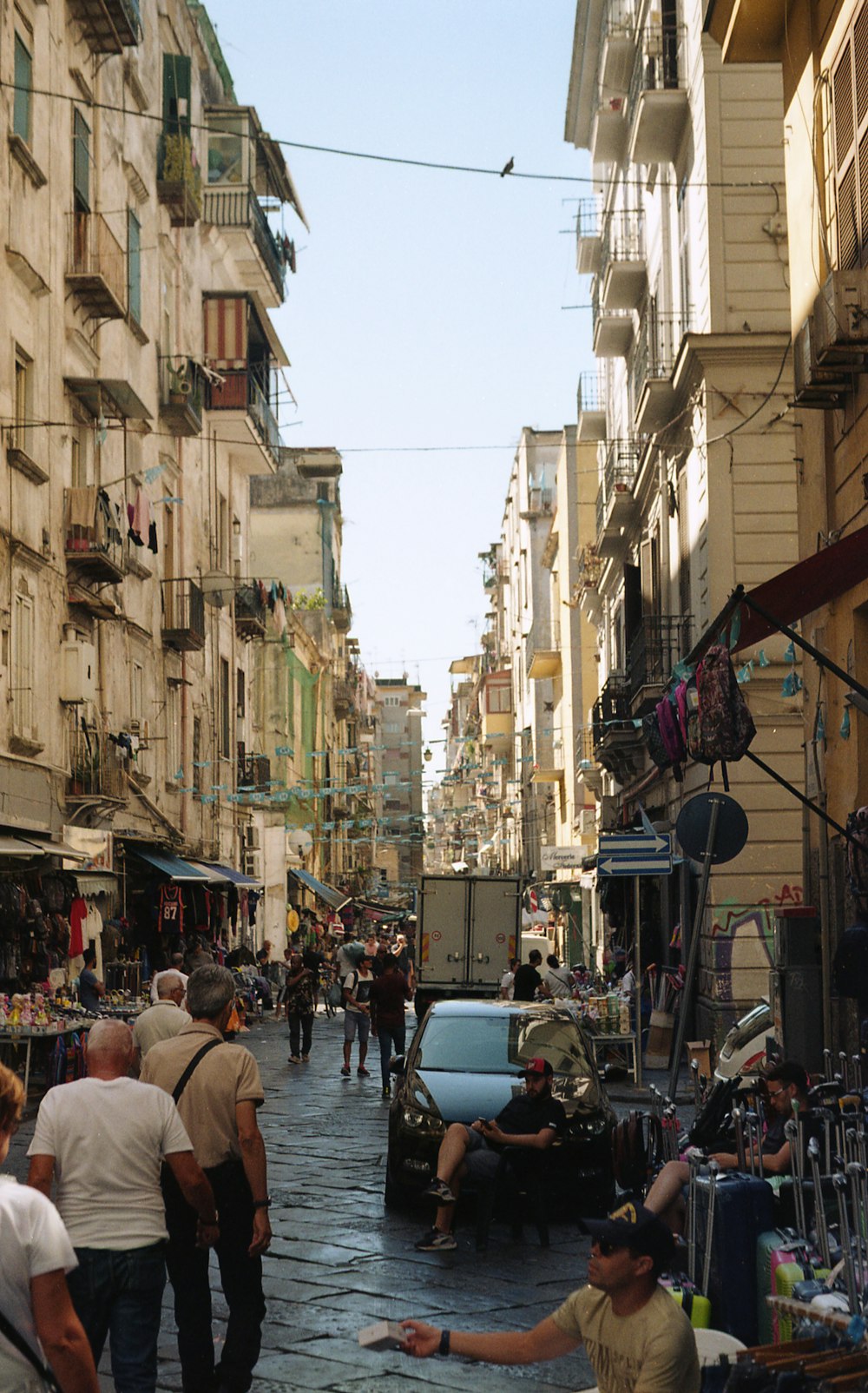 a group of people walking down a street next to tall buildings