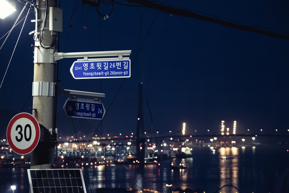 a street sign on a pole with lights in the background