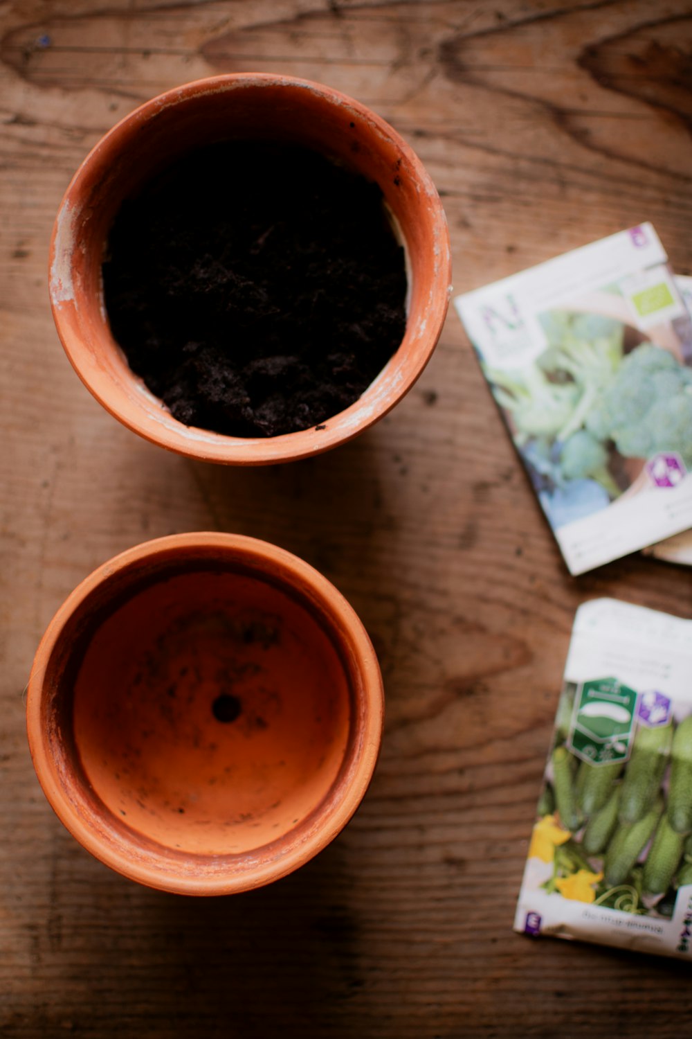 a wooden table topped with two cups filled with dirt