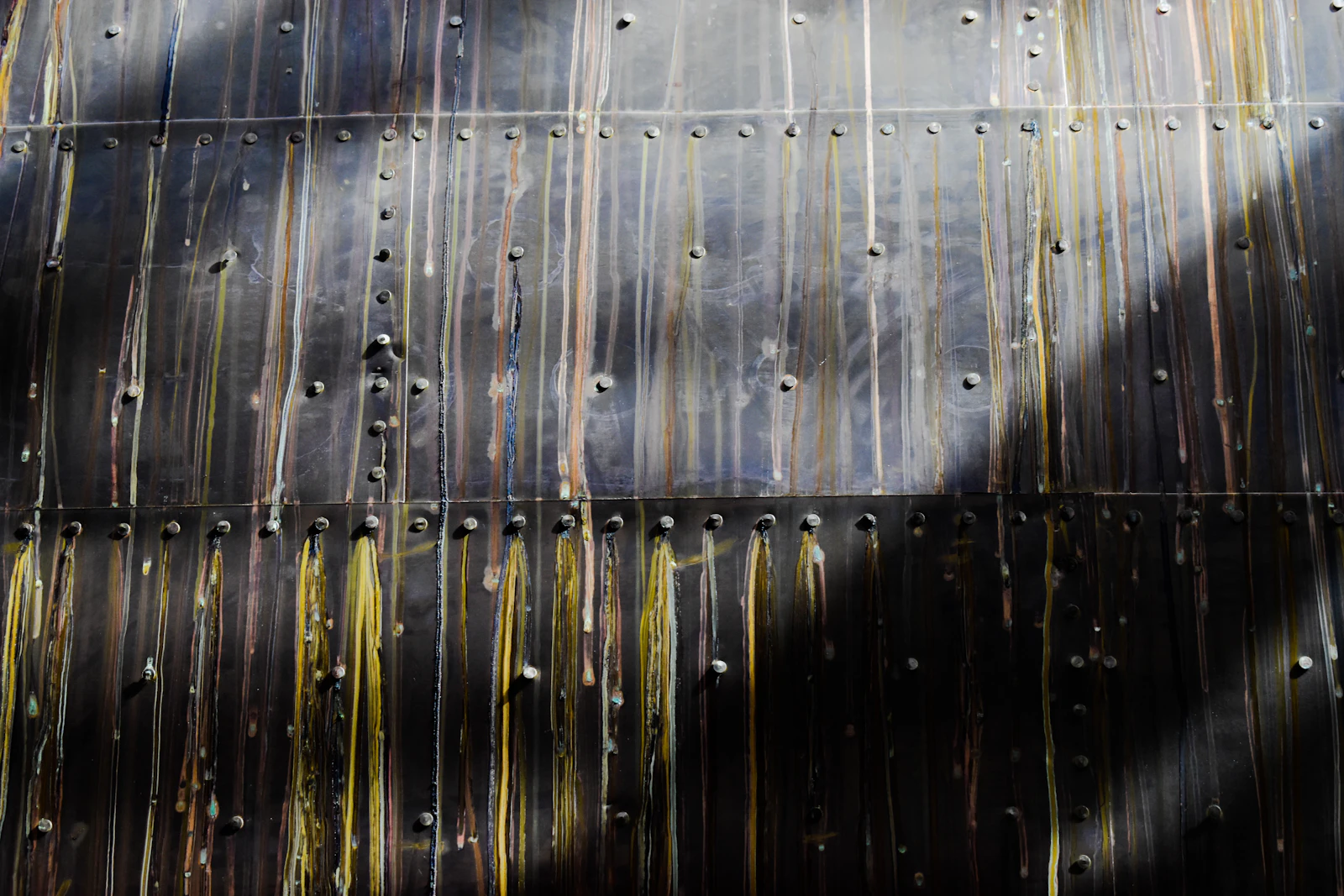 Photograph of Close view of riveted, rain-streaked metal plating on the underside of Cutty Sark’s hull.