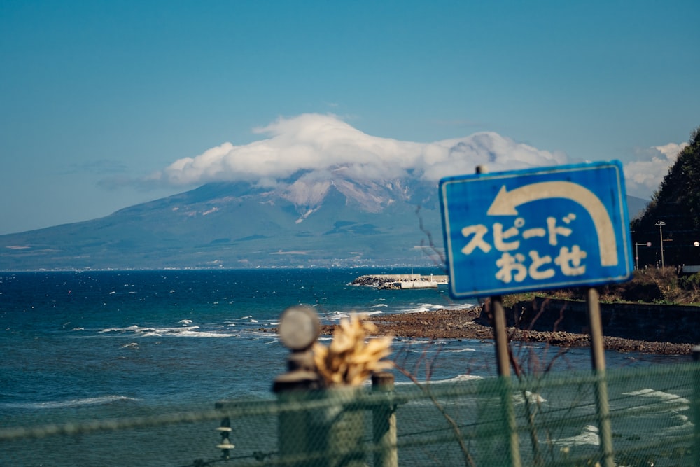Un letrero azul sentado al costado de una carretera junto al océano