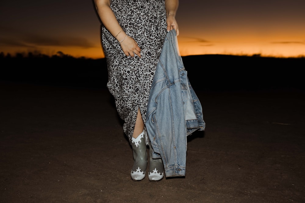 a woman in a dress holding a jean jacket