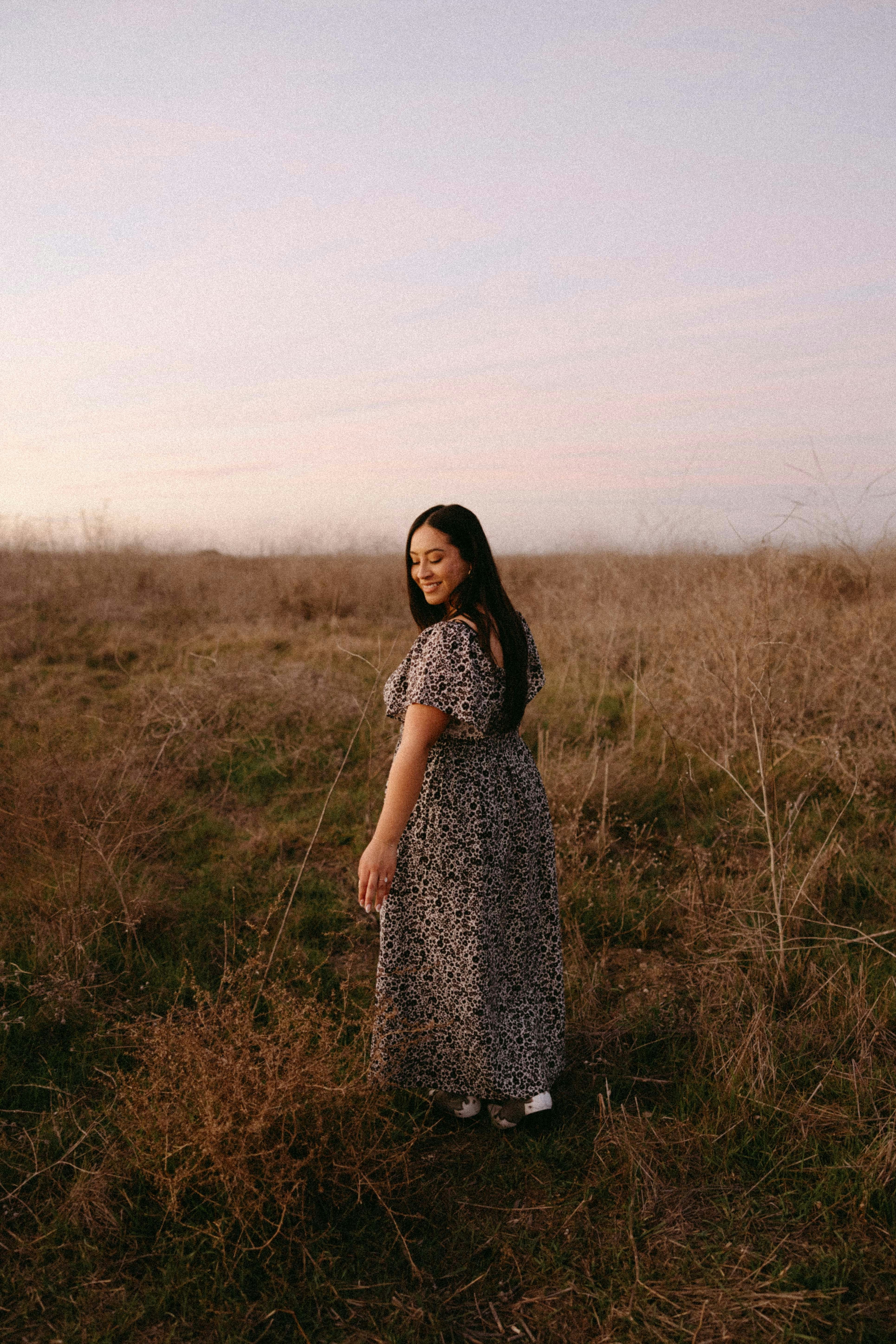 a woman in a dress standing in a field