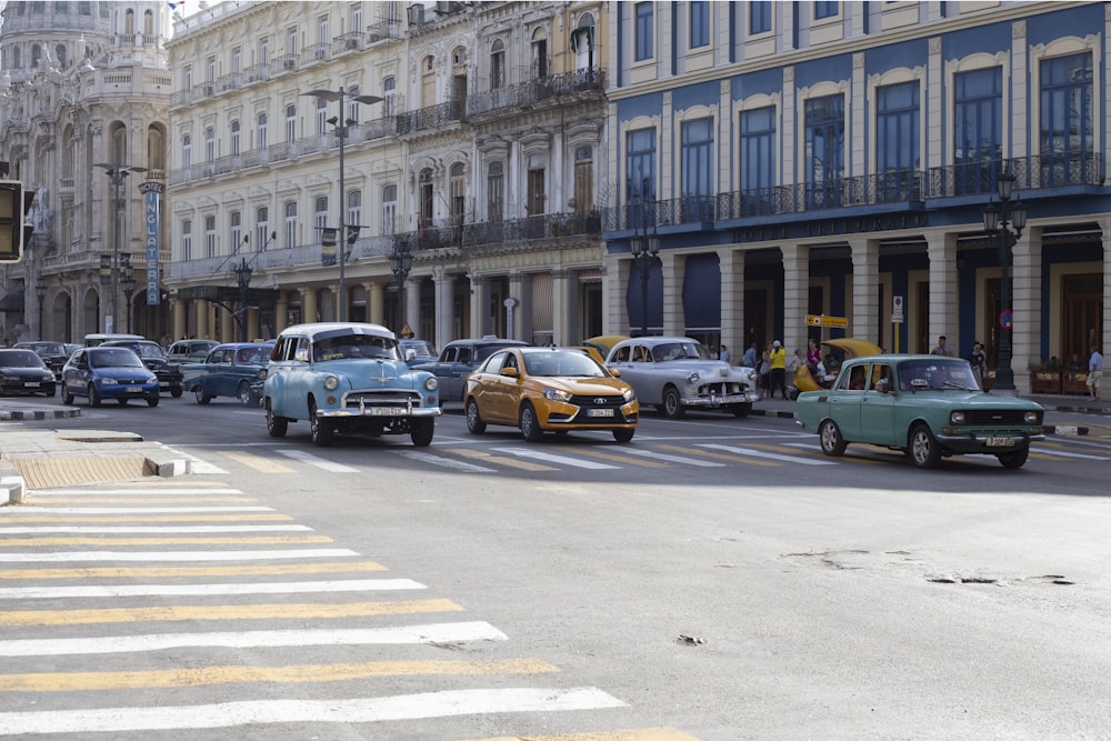 a group of cars driving down a street next to tall buildings