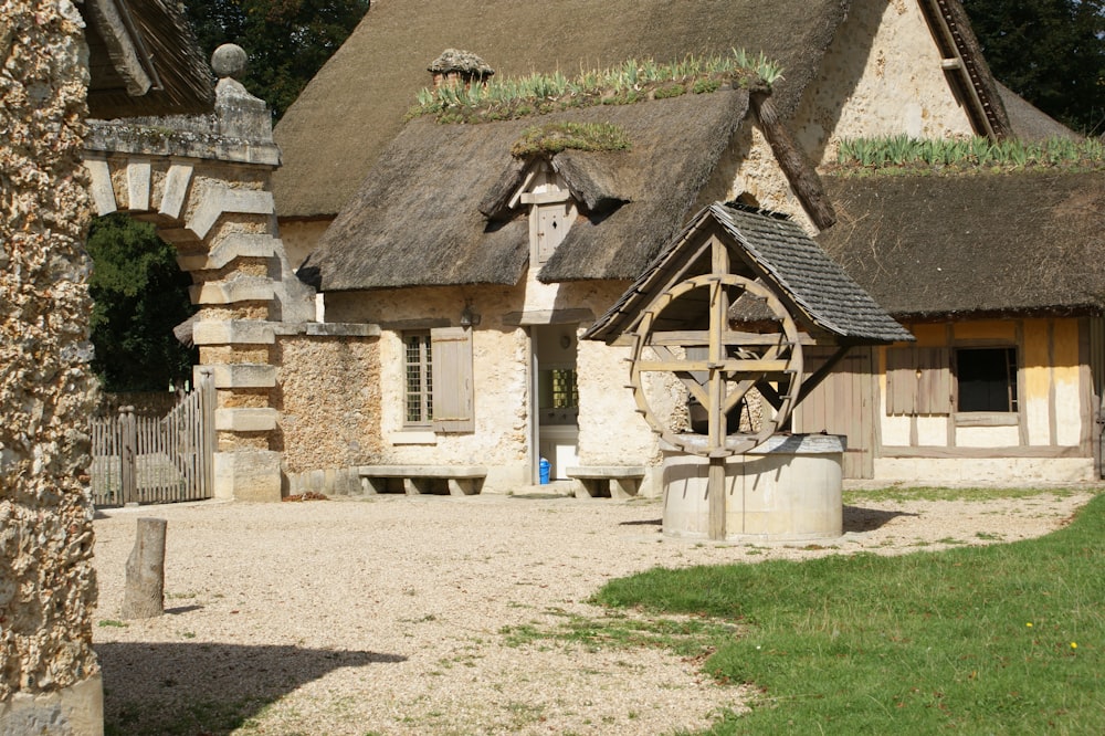 a stone building with a thatched roof and a water well