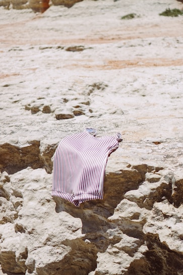a striped shirt is laying on a rock