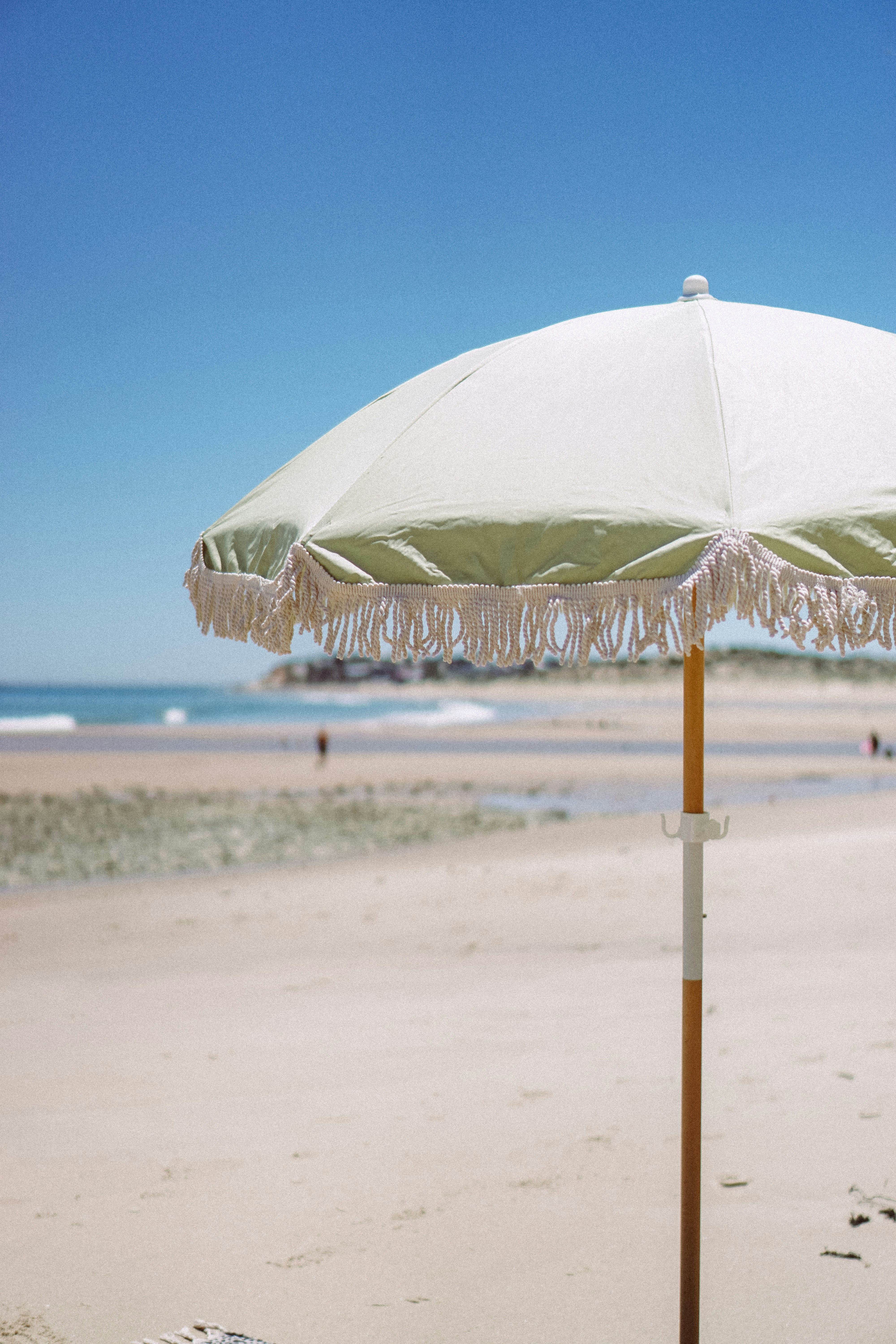 a white umbrella sitting on top of a sandy beach