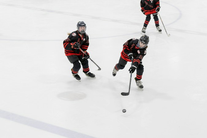 Young hockey player skating with a stick and puck during a development camp drill