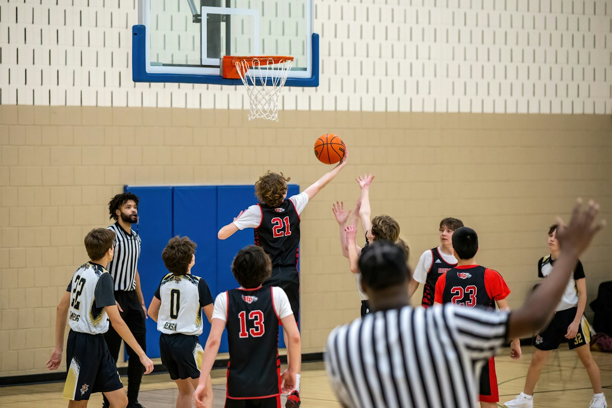 Young men playing basketball outdoors, demonstrating effective team management and practice planning in youth sports coaching.