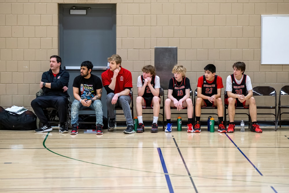 a group of young men sitting next to each other on a basketball court