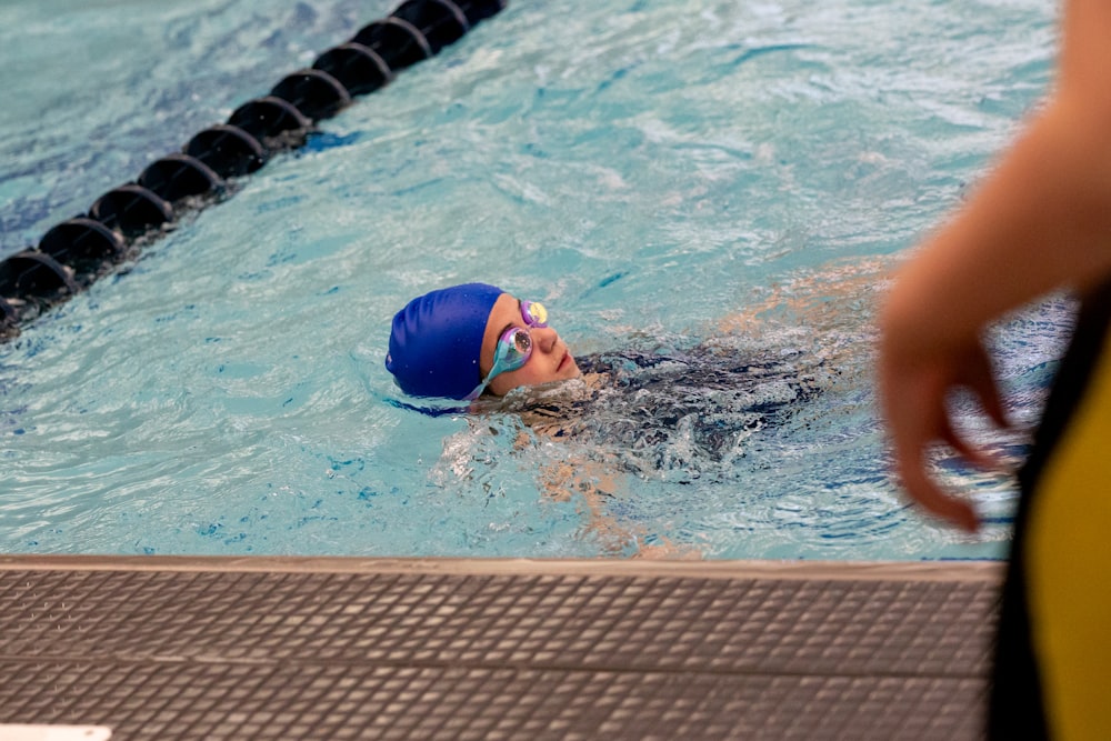 a woman swimming in a pool with a blue cap