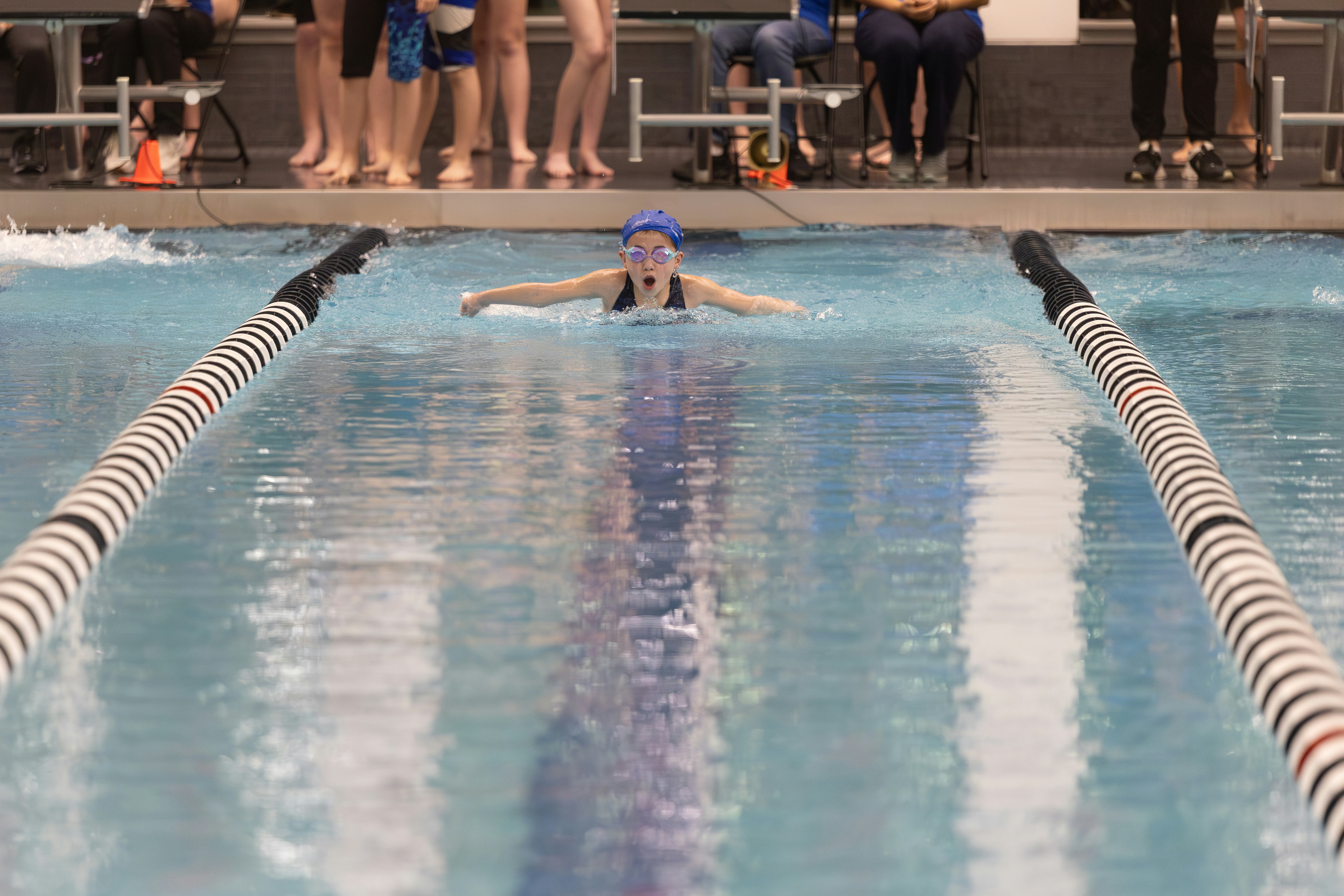 a woman swimming in a pool surrounded by people
