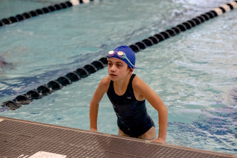 a young girl in a swimming pool wearing a swimming cap