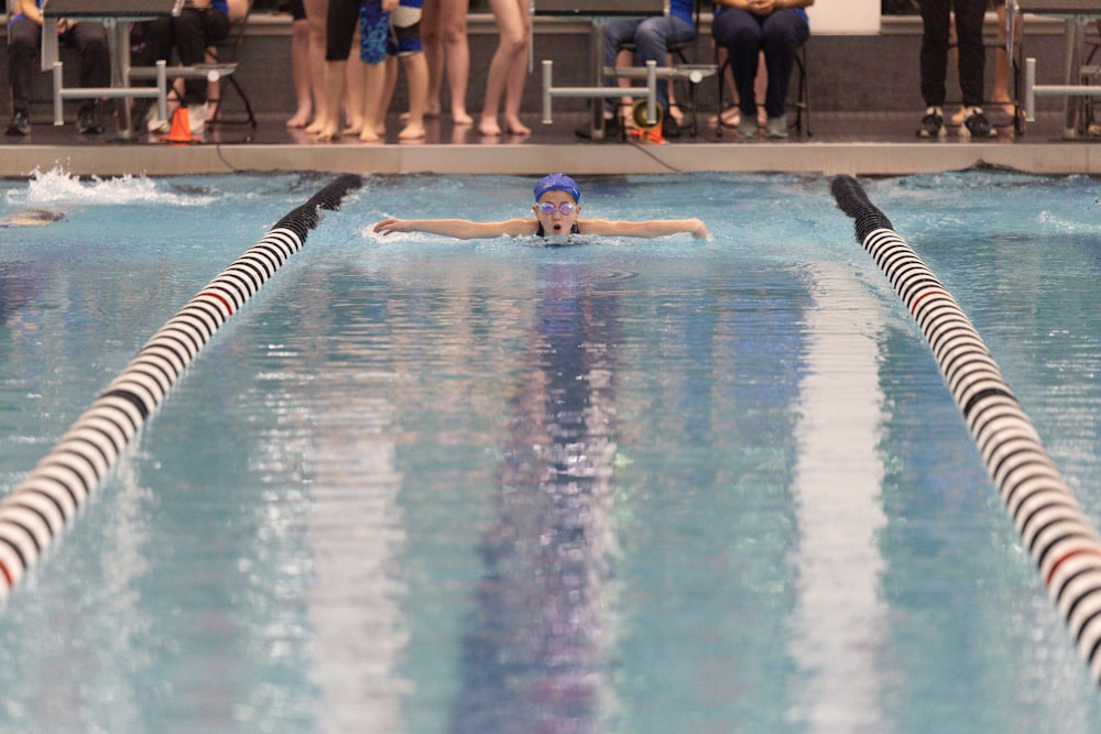 a person swimming in a pool with people watching