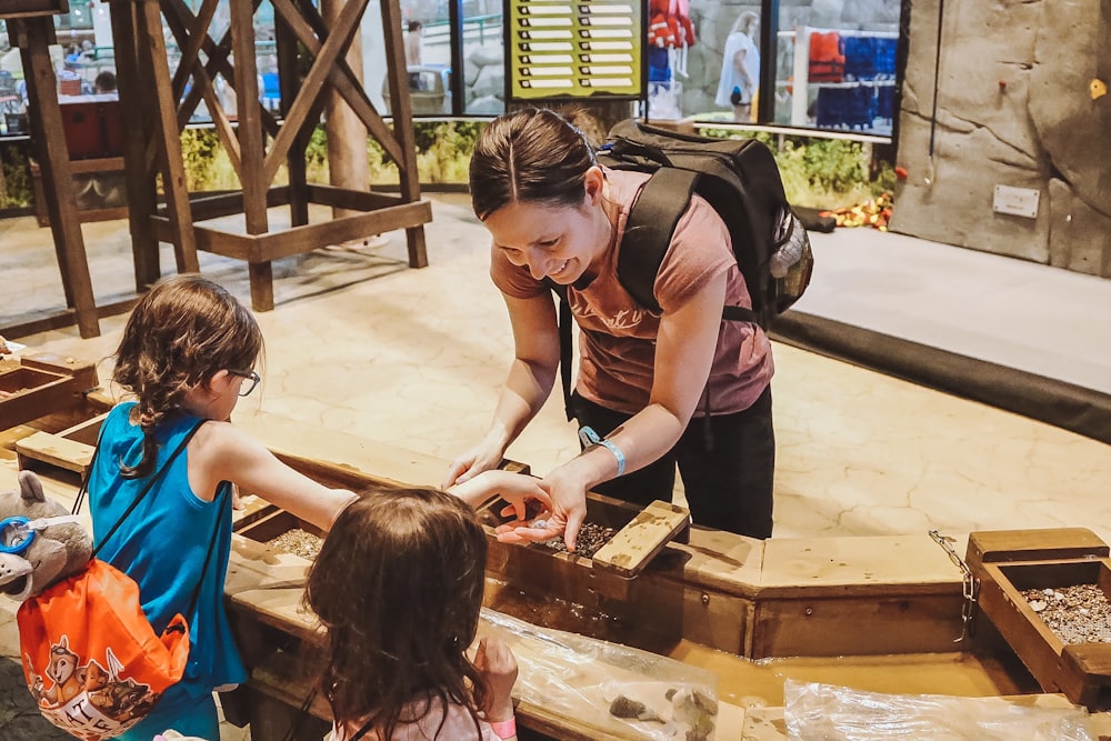 a woman and two little girls looking at a box