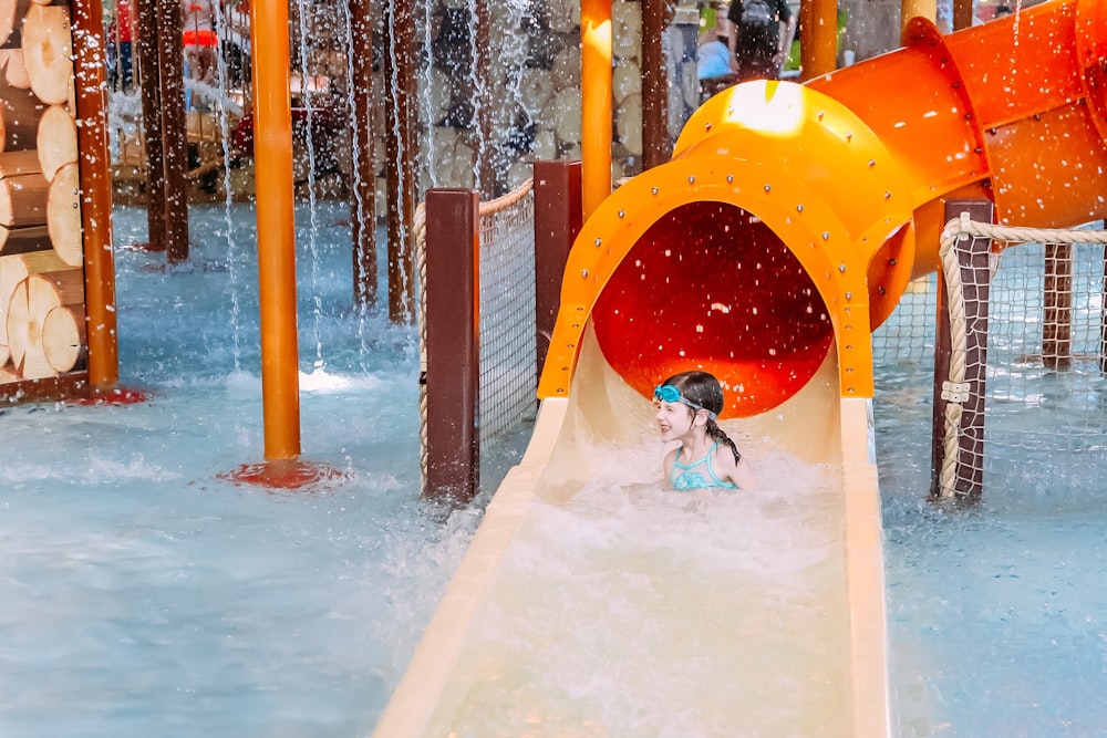 a child playing in a water park with a slide