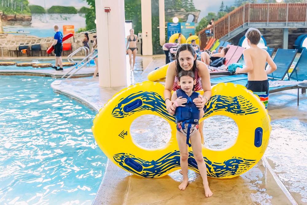 a woman holding a child on a raft in a pool