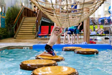 a man jumping into a swimming pool surrounded by logs