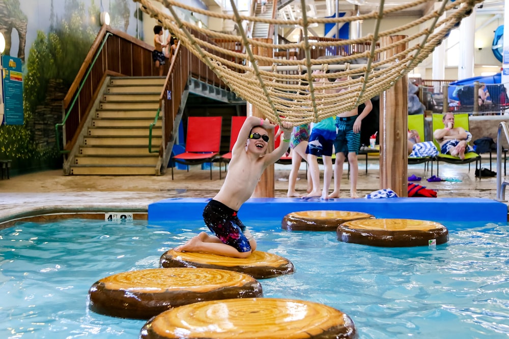 a man jumping into a swimming pool surrounded by logs