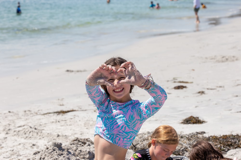 ein junges Mädchen sitzt an einem Strand neben einem anderen jungen Mädchen