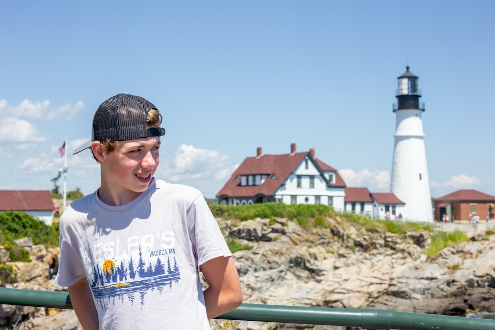 a young boy standing in front of a lighthouse