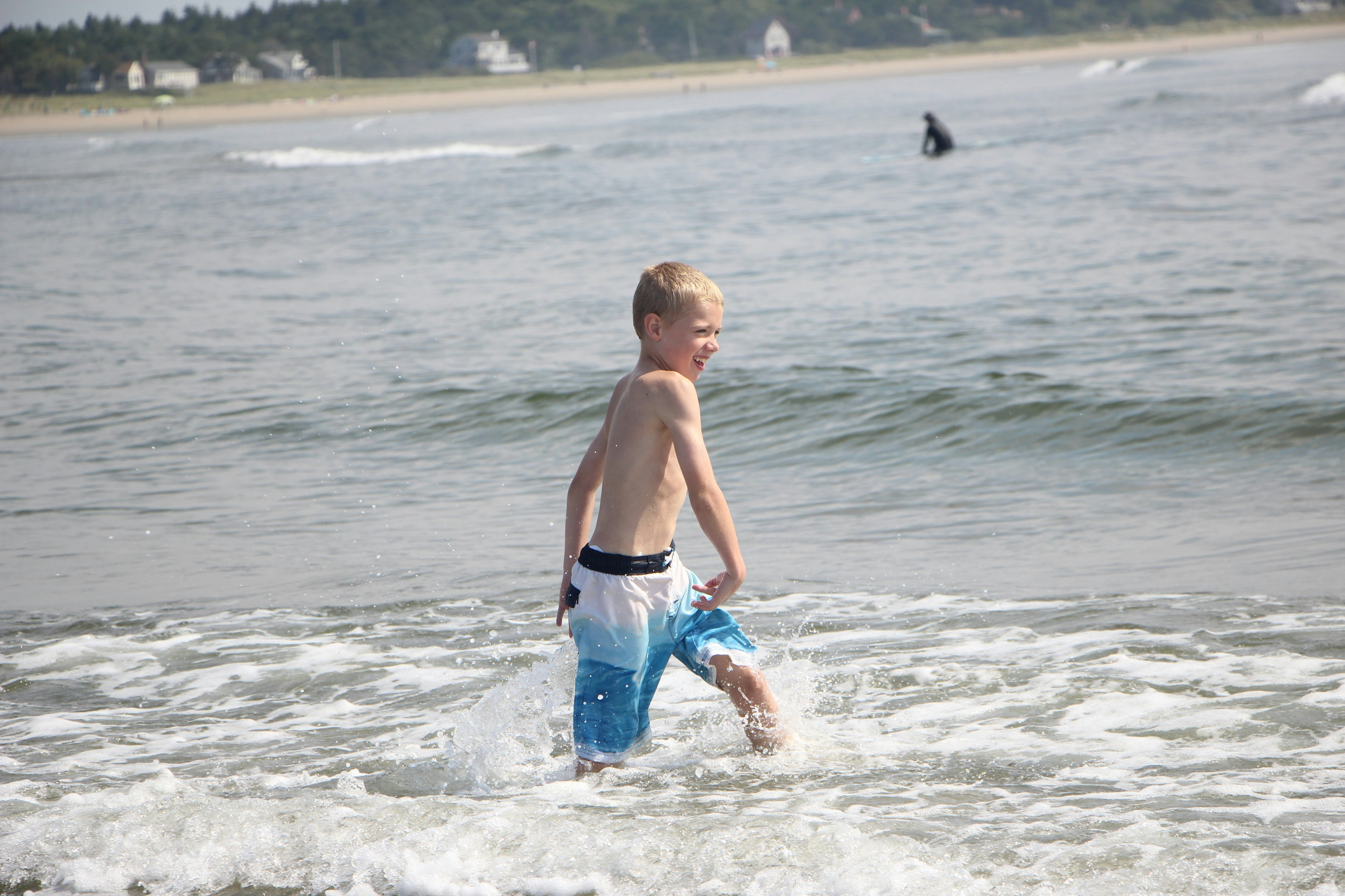 a young boy is playing in the water at the beach