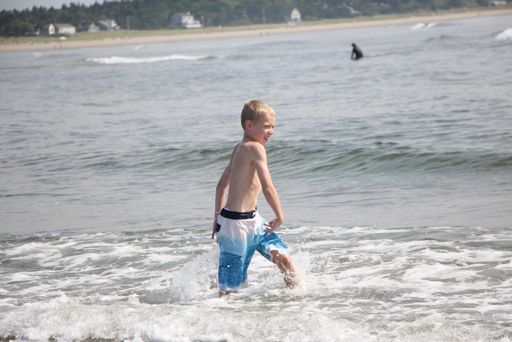 a young boy is playing in the water at the beach