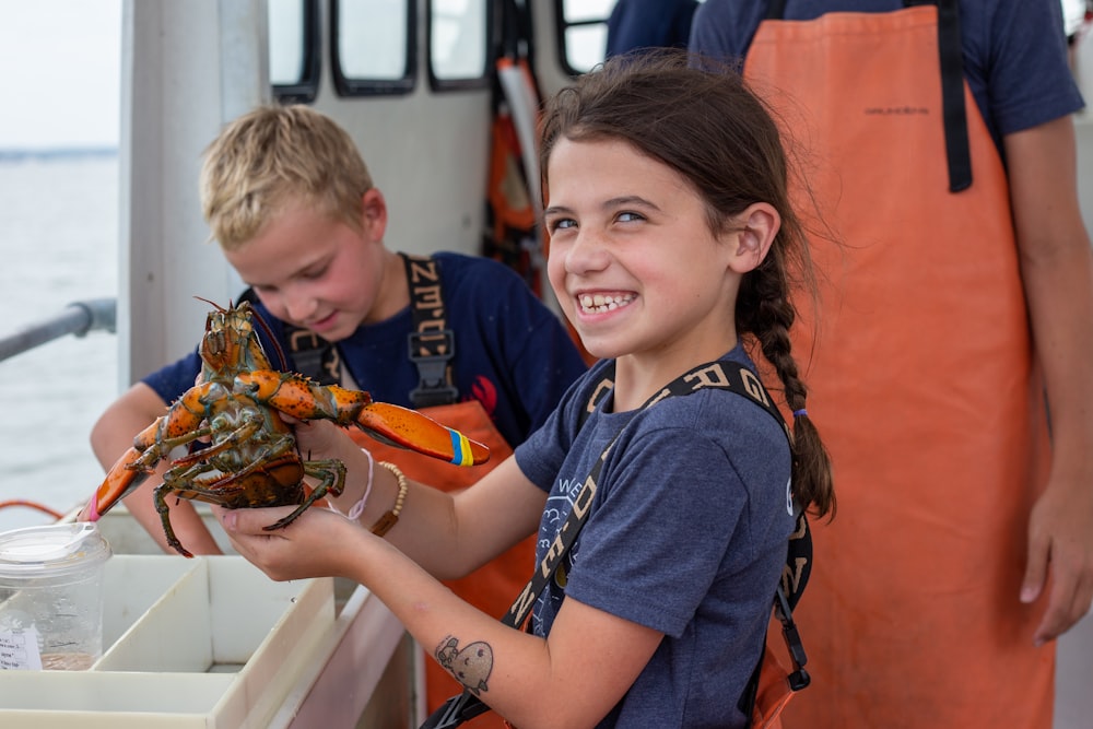 a boy and a girl holding a crab on a boat