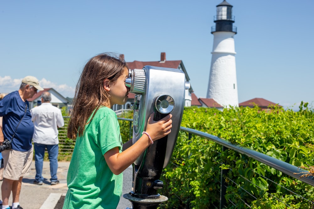 a little girl looking through a telescope at a lighthouse