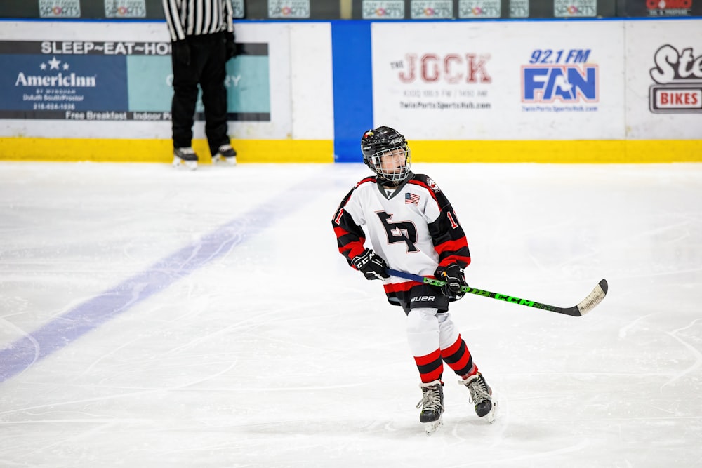 a young boy playing hockey on an ice rink