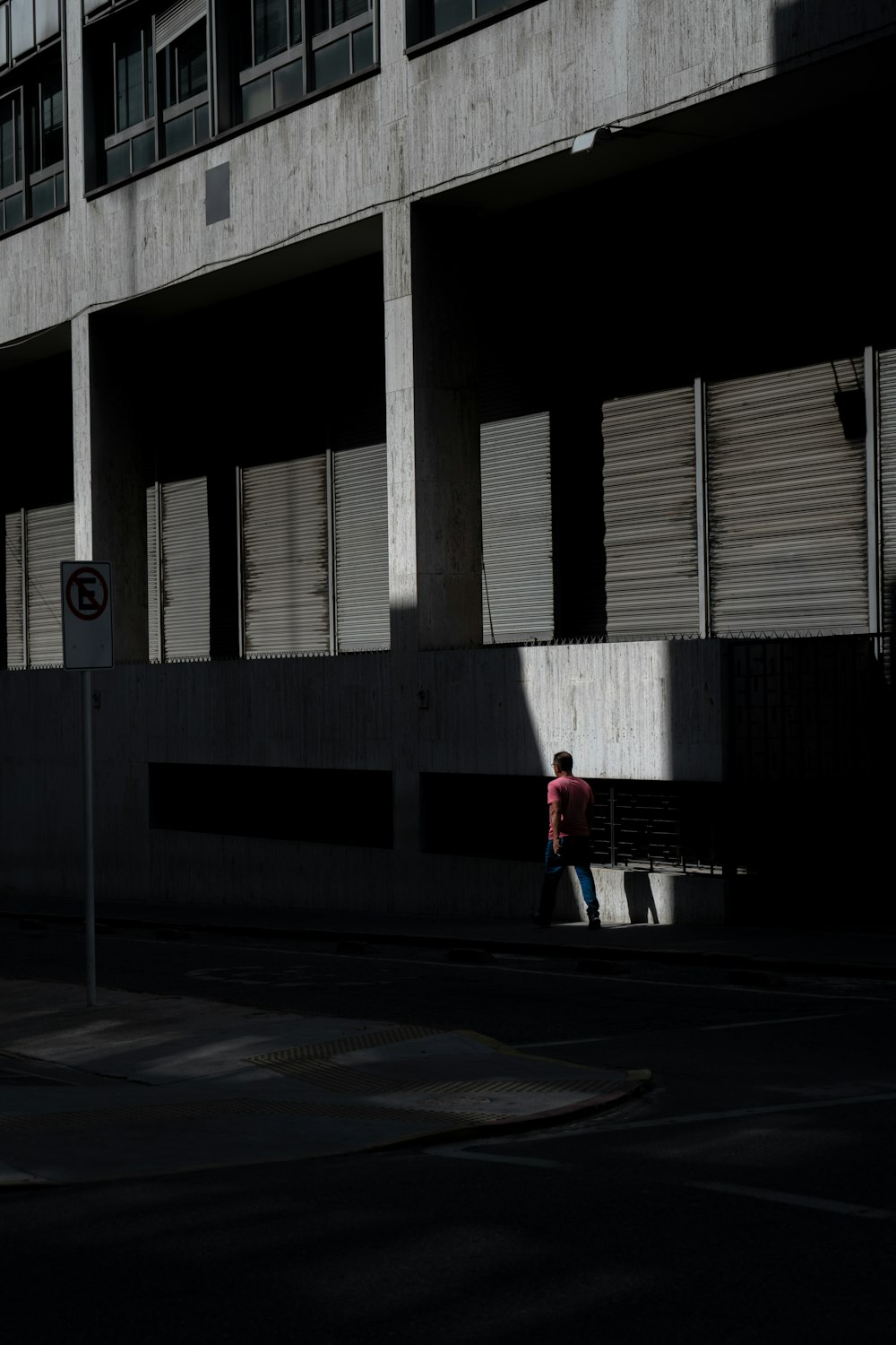 a man walking down a street next to a tall building