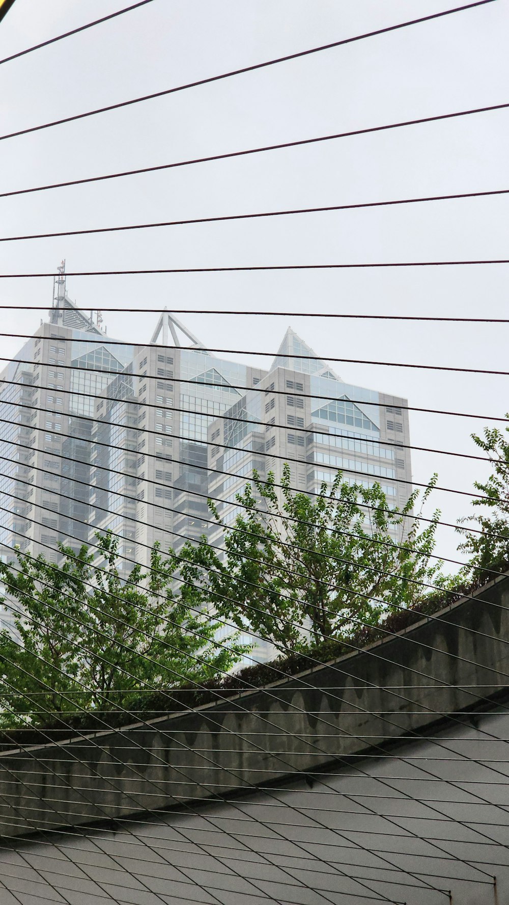 a view of a very tall building through some wires