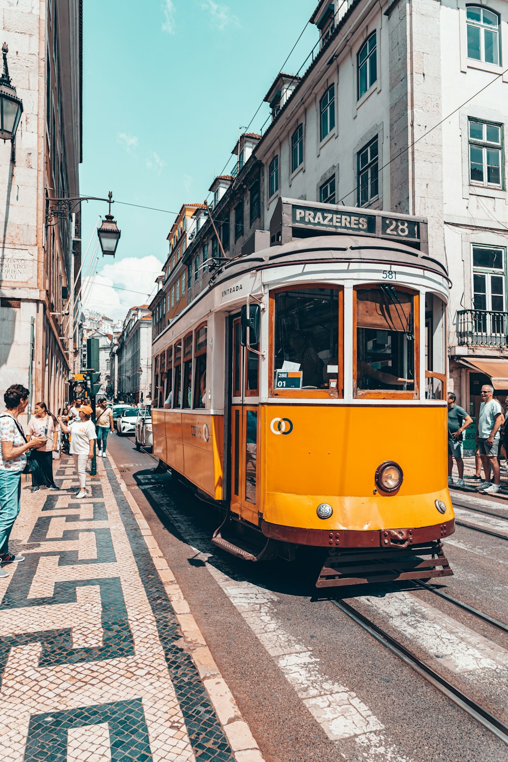 a yellow trolley car traveling down a street next to tall buildings