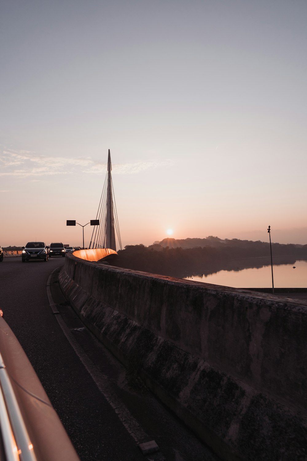 the sun is setting on a bridge over a body of water