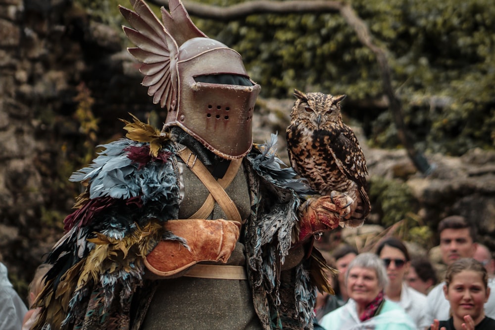 um homem vestido com armadura segurando uma coruja