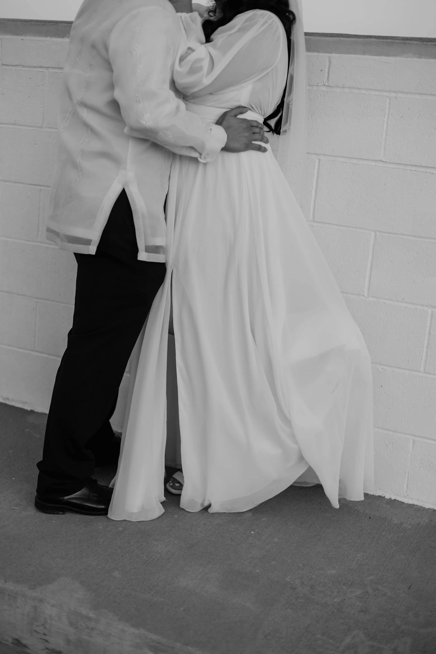 Couple in elegant wedding attire standing together with warm light at intimate city hall elopement ceremony location