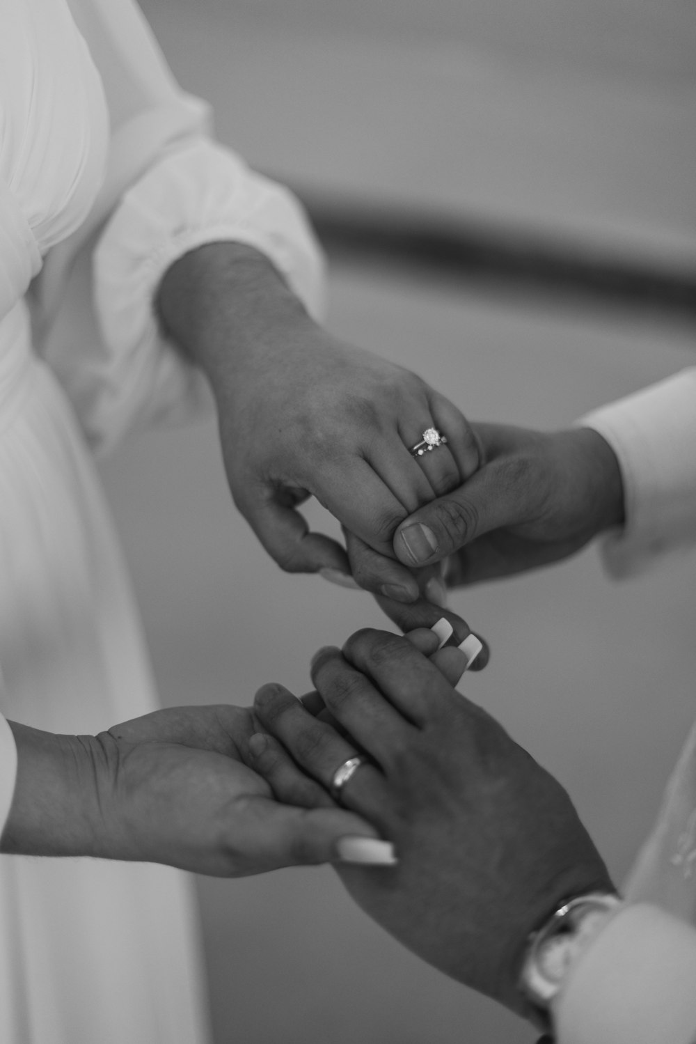 a black and white photo of a bride and groom holding hands