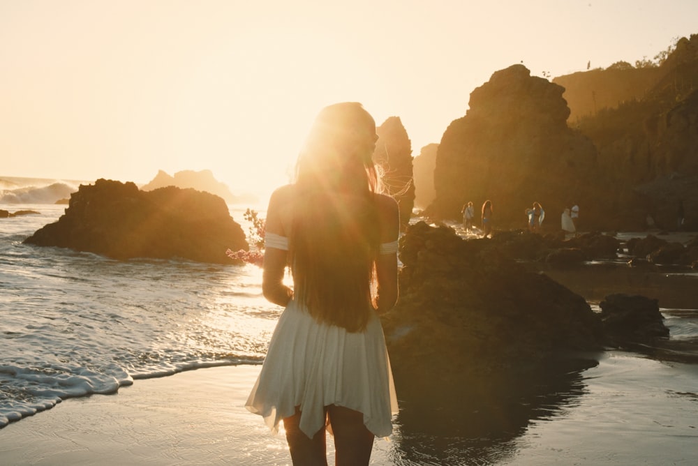 a woman standing on a beach next to the ocean