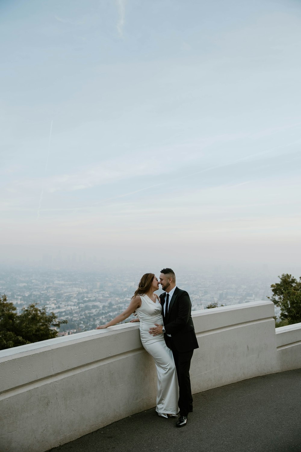 a bride and groom standing on top of a hill