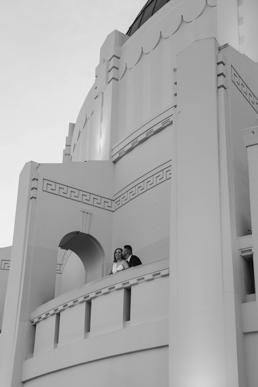 a black and white photo of a couple in front of a building