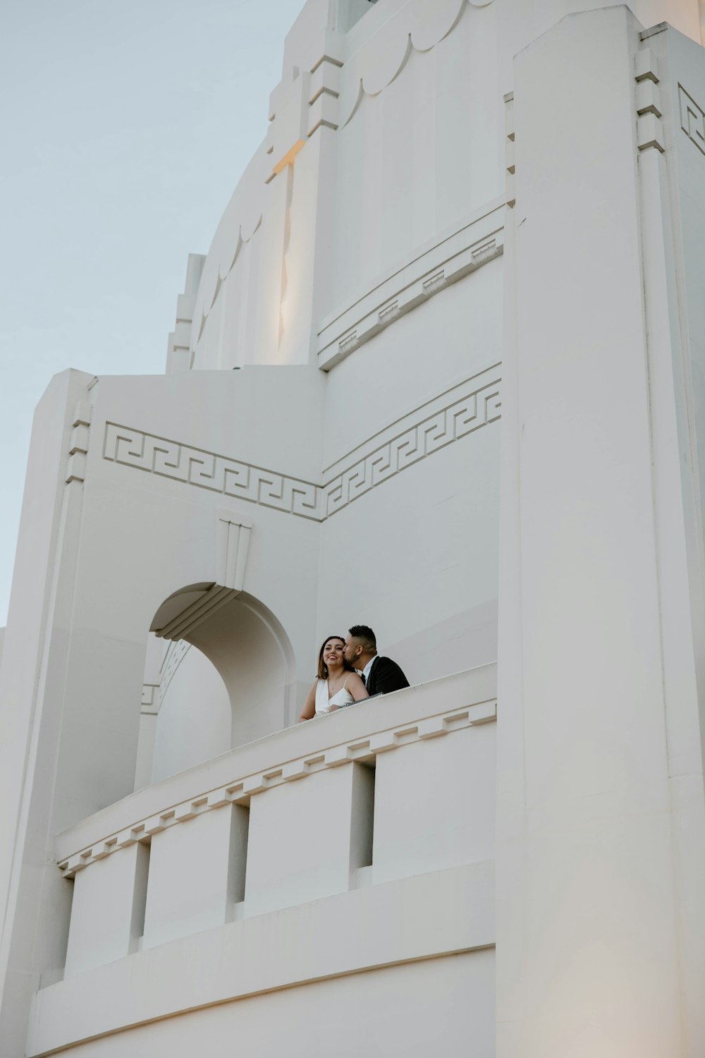 a bride and groom standing on the balcony of a building