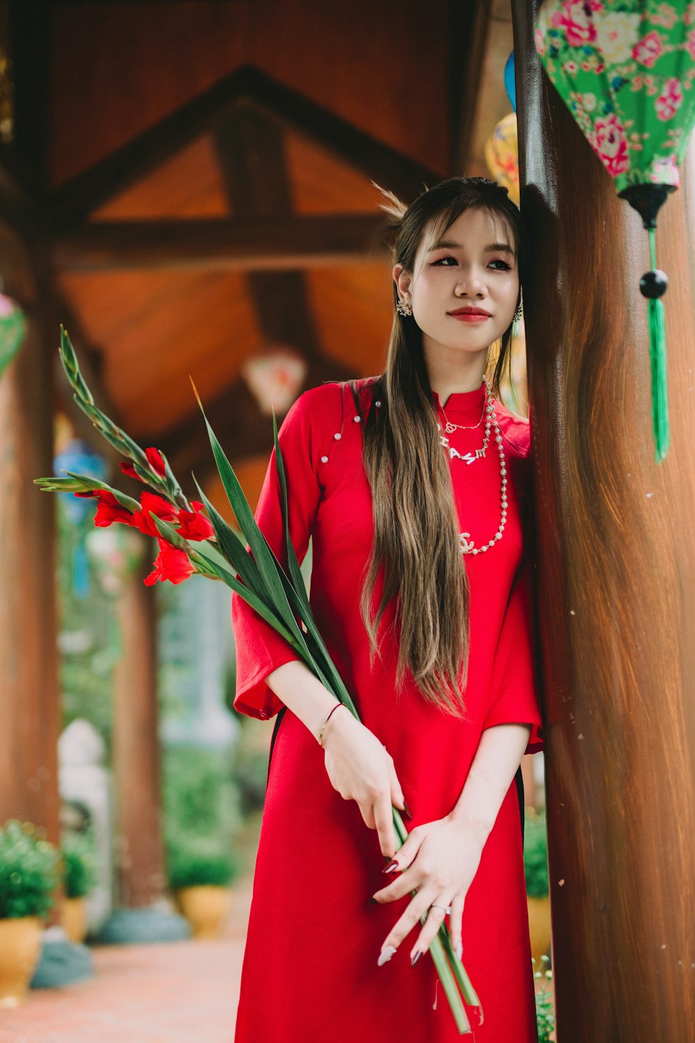 a woman in a red dress holding a bunch of flowers