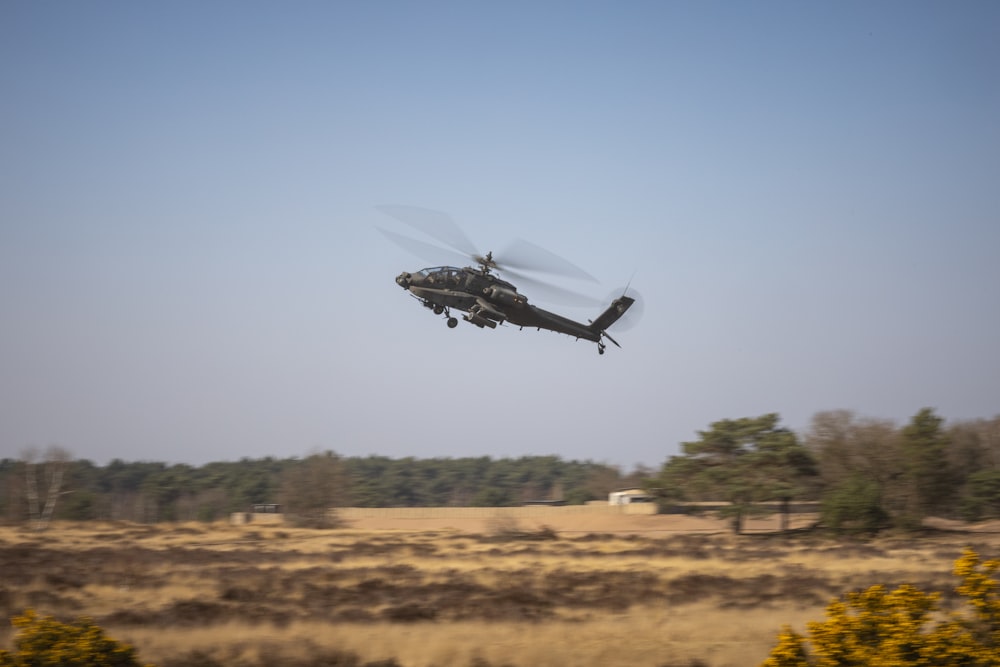 a helicopter flying over a dry grass field