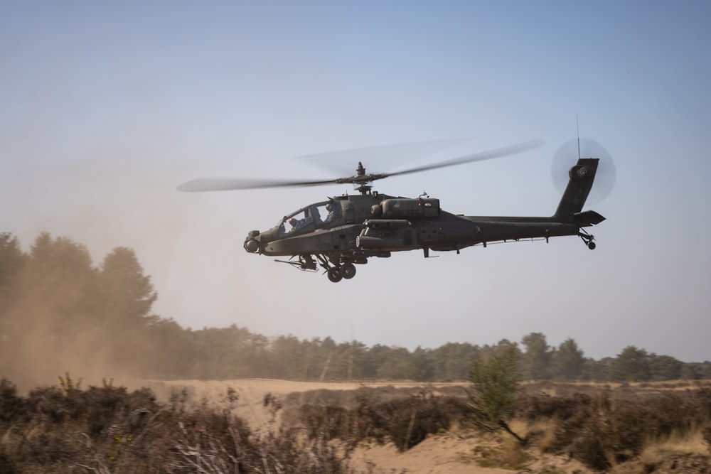 a helicopter flying low over a dirt field