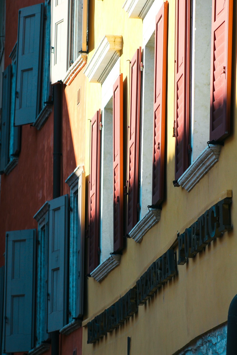 a yellow building with red shutters and a traffic light