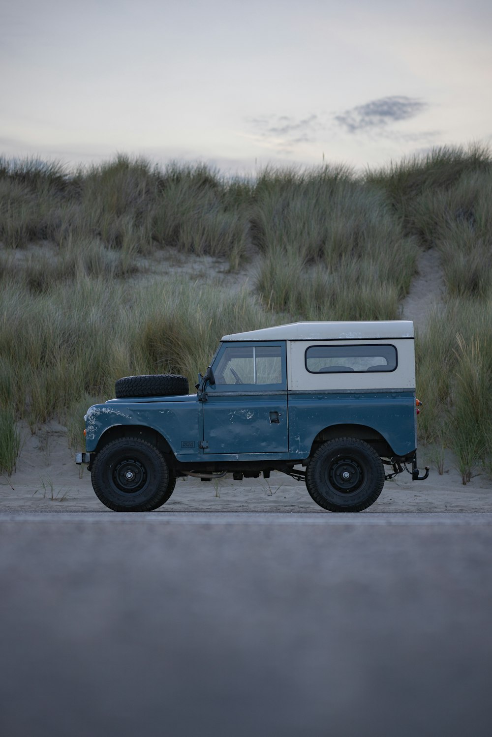 a blue and white truck parked on the side of a road