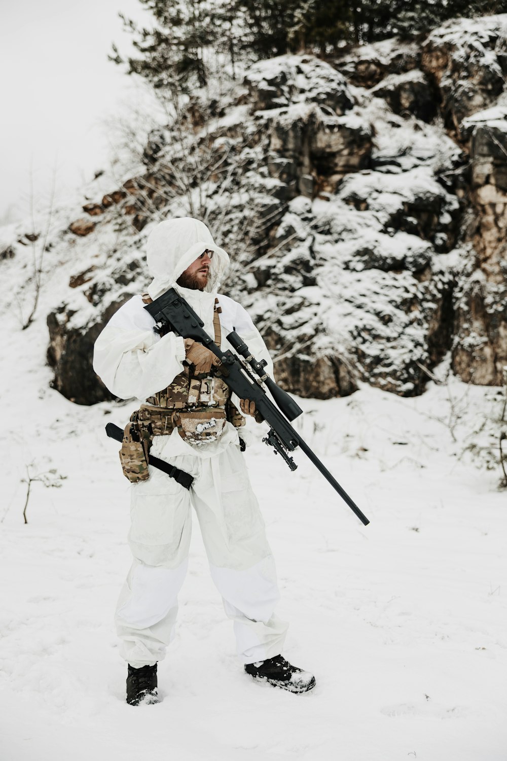 a man holding a rifle while standing in the snow